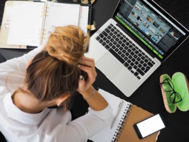 woman with head in hands at desk